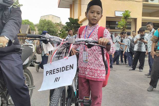 Seorang siswa SD Muhammadiyah Nanggulan saat membawa pulang sepeda Jokowi setelah berhasil menyebutkan lengkap Pancasila