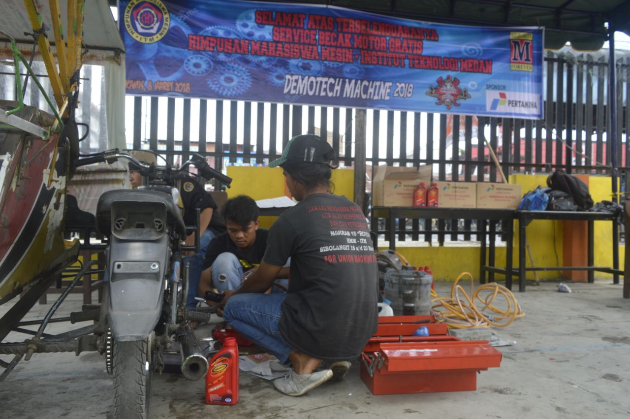 Mahasiswa ITM Medan sedang melakukan servis dan ganti oli gratis terhadap Becak Motor