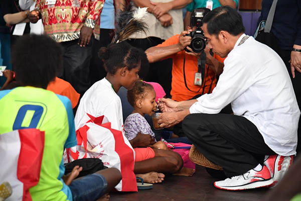 Presiden Jokowi dengan penuh perhatian menyuapi anak-anak Asmat