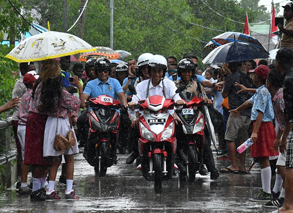 Presiden Jokowi dan Ibu Iriana melanjutkan perjalanan ke acara berikutnya dengan sepeda motor listrik walau diiringi hujan namun masyarakat Asmat tetap antusias