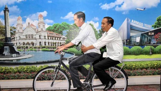Ekspresi Presiden Jokowi saat dibonceng oleh replika Jokowi dengan sepeda di Bandara Ahmad Yani, Semarang. (Foto: Facebook Presiden Joko Widodo)