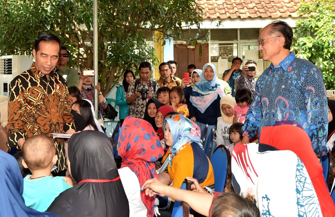 Presiden Jokowi dan Jim Yong Kim membagikan sejumlah buku tulis untuk anak-anak dan mencicipi penganan penambah gizi anak.